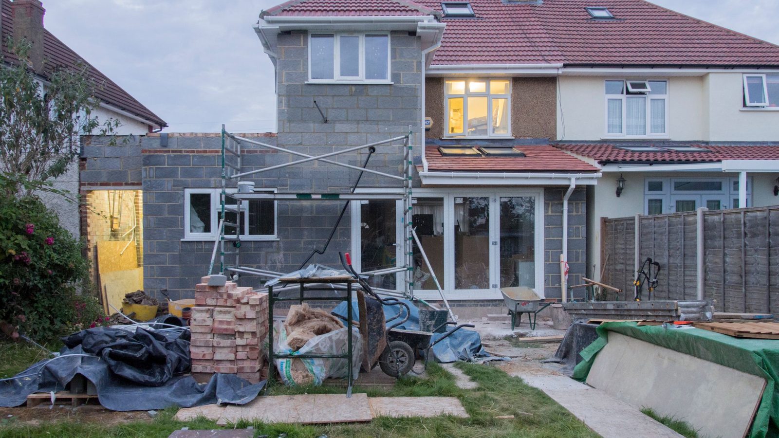Casa in ristrutturazione con il ponteggio, i mattoni e i materiali del cantiere in giardino