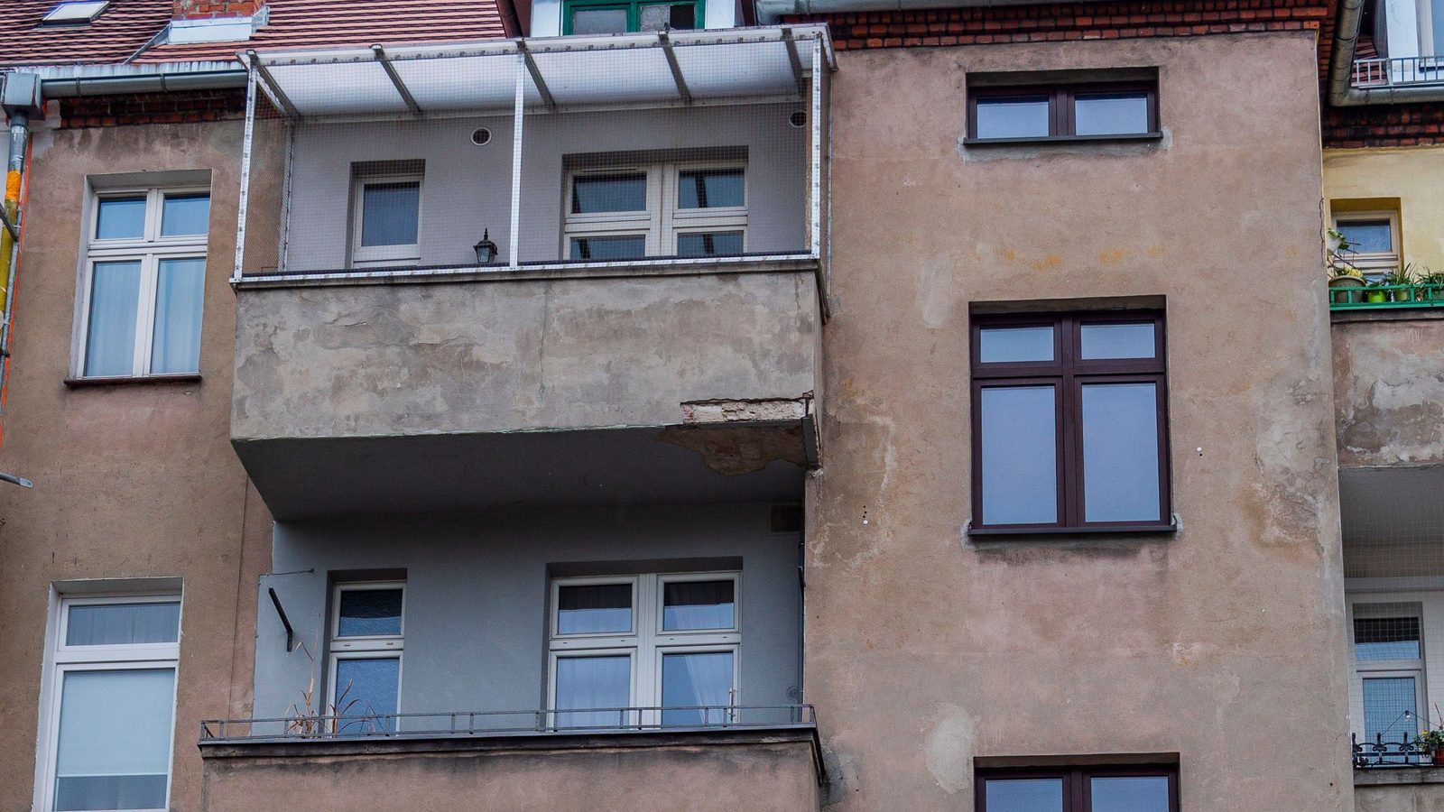 Facciata di un vecchio condominio con balconi sovrapposti e intonaco consumato